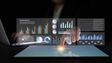 Analitik çizelgelerle gelecekteki veri yönetim arayüzünü gösteren profesyonel bir sahne. Bir birey dokunmatik ekran teknolojisiyle etkileşime girer, veri odaklı karar verme mekanizmasını vurgular. Gantry