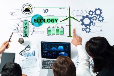 Çeşitli bir ekip, sürdürülebilir kalkınma ve ekolojik farkındalık için yenilikçi stratejiler üzerinde odaklanarak dijital tablolar ve rüzgar enerjisi grafikleri üzerinde işbirliği yapıyor. Çapraz