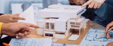 Bir grup mimari tasarım işbirliğine girişerek, modern çalışma alanındaki planlar ve belgeler arasında bir modeli tutkuyla tartışıyor, takım çalışmasını ve yaratıcılığını resmediyor. SACTR