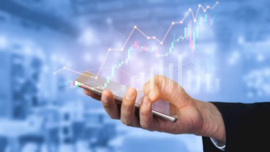 Bir işadamı dijital grafik ve grafikler gösteren, çağdaş ofis ortamındaki büyüme ve başarıyı sembolize eden bir akıllı telefonla etkileşime girer. Kafa derisi