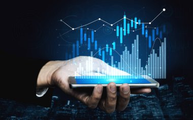 Bir el, yatırım analizindeki modern teknoloji rolünü sembolize eden, soyut grafik ve grafiklerle canlı finansal verileri gösteren bir akıllı telefonu tutuyor. Kafa derisi