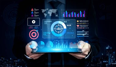 Karanlık bir şehir ortamında elinde canlı grafikler ve etkileşimli elementlerle dolu modern bir veri analiz arayüzünü gösteren bir tablet tutan bir işadamı görülüyor. Gantry