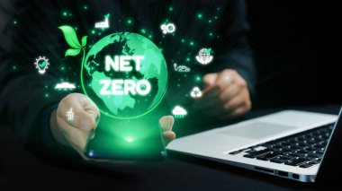 Modern teknolojide sürdürülebilirlik ve çevresel sorumluluğun önemini vurgulayan akıllı telefon ve dizüstü bilgisayarla net sıfır kavramını gösteren profesyonel bir ortam. Dörtgen