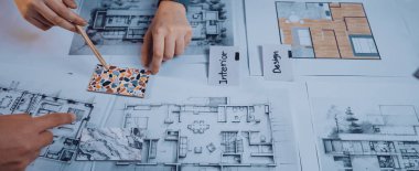 Tasarımcıların elleri aktif olarak renk örnekleri seçmek ve bir iç tasarım projesi için masadaki mimari planları analiz etmek için bir işbirliği oturumuna katılıyorlar. SACTR