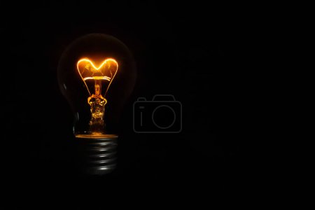 bombilla incandescente en forma de corazón sobre fondo negro para el día de San Valentín