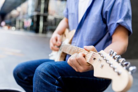 Photo for Hands of musician tuning his guitar outside - Royalty Free Image