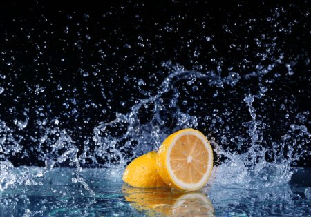 Téléchargez les photos : Citron tranché dans l'eau sur fond noir - en image libre de droit