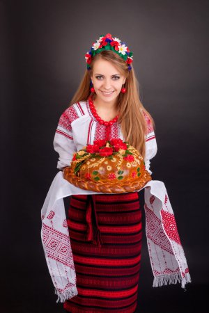 Photo for Young woman in ukrainian clothes, with garland and round loaf on black background - Royalty Free Image