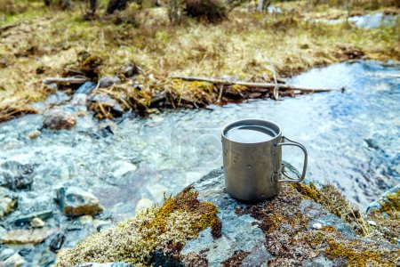 Téléchargez les photos : Coupe en titane de voyage. Déjeuner pendant le voyage à l'état sauvage. Mode de vie camping
. - en image libre de droit