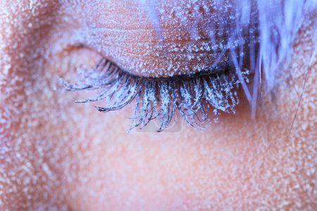 Téléchargez les photos : Œil de femme gelé recouvert de givre. Gros plan de l'œil gauche avec des cils bleus - en image libre de droit