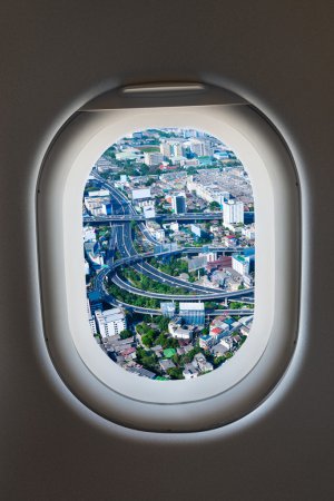 Photo for Airplane window from interior of aircraft with view of complex highway interchange  snaking around tall buildings at day. - Royalty Free Image