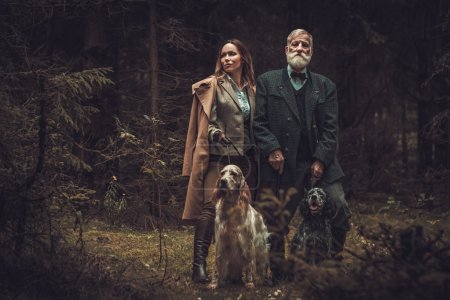 Two hunters with dogs and shotguns in a traditional shooting clothing