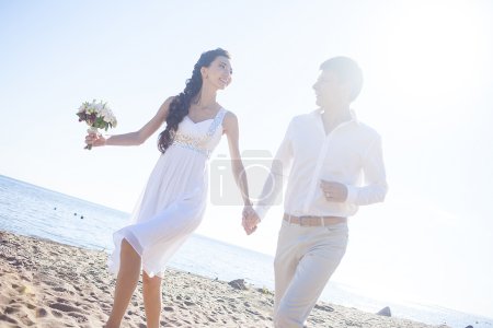 Acabo de casarme feliz pareja corriendo en una playa de arena
