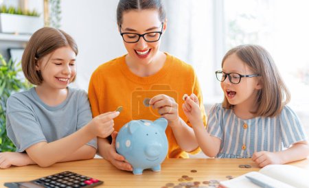 Mujer y niños sentados en el escritorio con una alcancía están calculando los gastos, la gestión del presupuesto familiar.