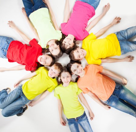 Foto de Niños del grupo feliz aislados en fondo blanco. Adolescente sonriente yaciendo en círculo. Fraternidad niños y niñas - Imagen libre de derechos