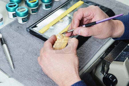 Foto de Técnico dental trabajando en dientes postizos. mesa con herramientas dentales - Imagen libre de derechos