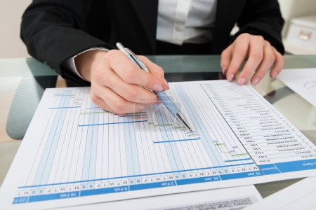 Photo for Close-up Of Businesswoman With Pen Working On Gantt Chart At Desk - Royalty Free Image