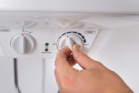 Photo for Close-up Of Person Hand Turning The Knob Of Electric Boiler - Royalty Free Image