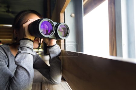 Mujer asiática usando prismáticos para observación de aves
