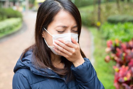 Téléchargez les photos : Asiatique jeune femme malade et portant un masque protecteur à l'extérieur - en image libre de droit