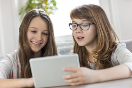 Foto de Hermanas usando tableta digital en la mesa en casa - Imagen libre de derechos