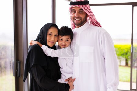 Photo for Portrait of happy young muslim family of three standing together at home - Royalty Free Image