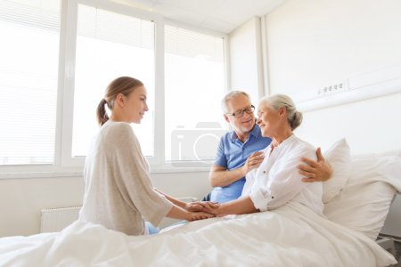 familia feliz visitando a la mujer mayor en el hospital