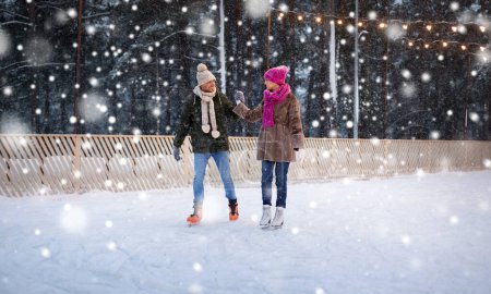 feliz pareja cogida de la mano en pista de patinaje