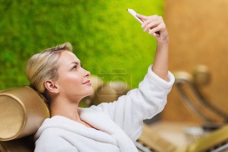 beautiful young woman with smartphone at spa