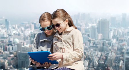 chicas felices con la computadora de la tableta sobre la ciudad
