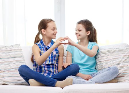 Niñas felices mostrando la forma del corazón signo de mano
