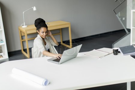 Téléchargez les photos : Jeune femme utilisant un ordinateur portable dans le bureau - en image libre de droit