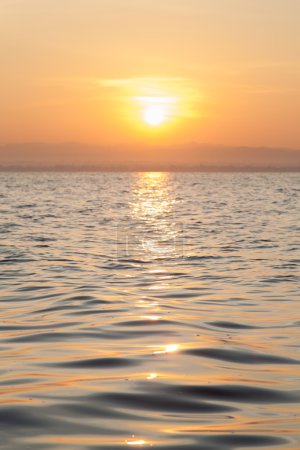 Foto de El sol sale por la mañana. Frente a un lago que refleja la luz del sol
. - Imagen libre de derechos