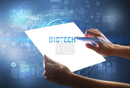 Photo for Hand holdig futuristic tablet with BIOTECH inscription, new technology concept - Royalty Free Image