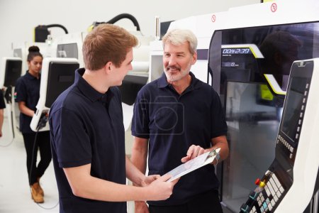 Apprenti travaillant avec un ingénieur sur des machines CNC
