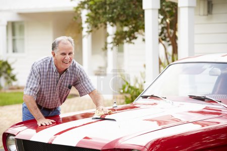 Hombre mayor limpieza coche restaurado

