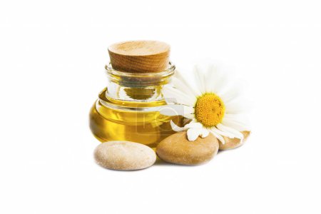 Foto de Aceite de manzanilla para el tratamiento de spa con piedras de flores y masajes aislados - Imagen libre de derechos