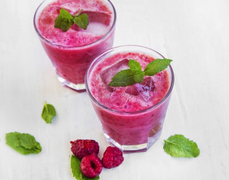 Foto de Batidos de frambuesas heladas frescas con hojas de menta fresca y frutas de frambuesa - Imagen libre de derechos