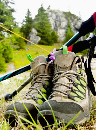 Foto de Botas de montaña y postes de trekking en el fondo al aire libre con rocas y árboles - Imagen libre de derechos