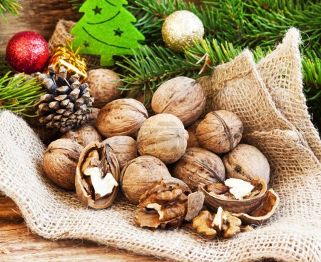 Foto de Nueces agrietadas, nueces con nueces enteras, decoración navideña y abeto en el fondo - Imagen libre de derechos
