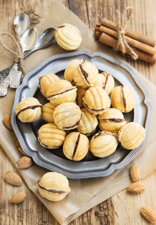 Foto de Galletas en forma de nueces con relleno de chocolate, galletas caseras dulces con almendras y palitos de canela - Imagen libre de derechos