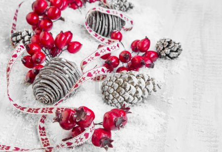 Foto de Cinta decorativa de Navidad con bayas rojas y conos de pino en la nieve sobre madera pintada - Imagen libre de derechos