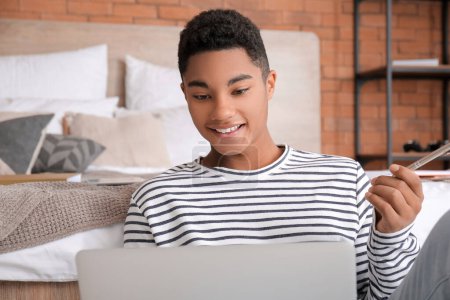 Foto de Estudiante afroamericano con portátil que estudia online en casa - Imagen libre de derechos