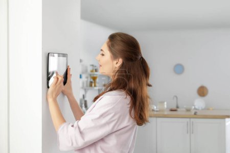 Mujer usando el panel de control del sistema de seguridad del hogar inteligente