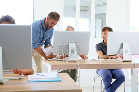 Téléchargez les photos : Enseignant avec groupe d'étudiants en classe travaillant sur bureau - en image libre de droit