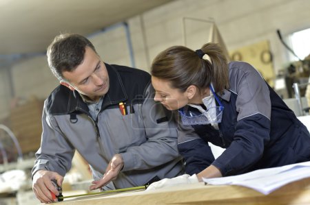 Photo for Workers measuring wood plank in manufacture with tape - Royalty Free Image