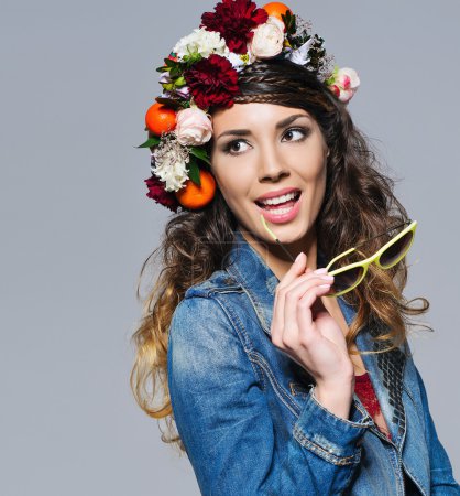 Hermosa mujer en corona de flores sosteniendo gafas de sol
