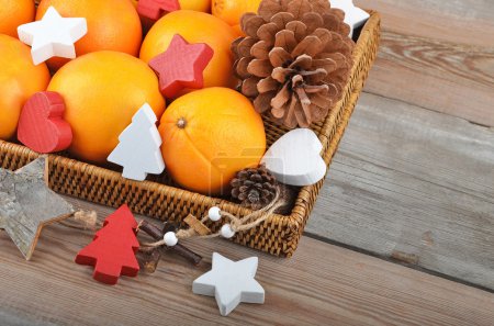 Photo for Orange in wickered tray on wooden background with Christmas decor - Royalty Free Image