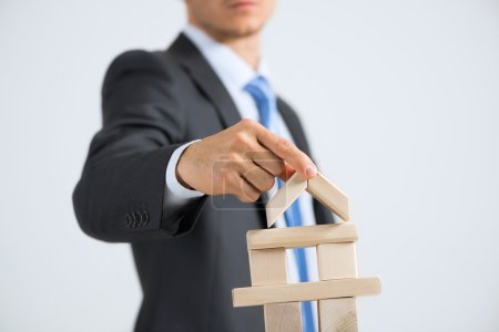 Photo for Young handsome businessman building tower of wooden blocks - Royalty Free Image