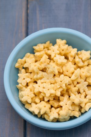 Photo for Corn flakes in blue plastic bowl on blue wooden background - Royalty Free Image